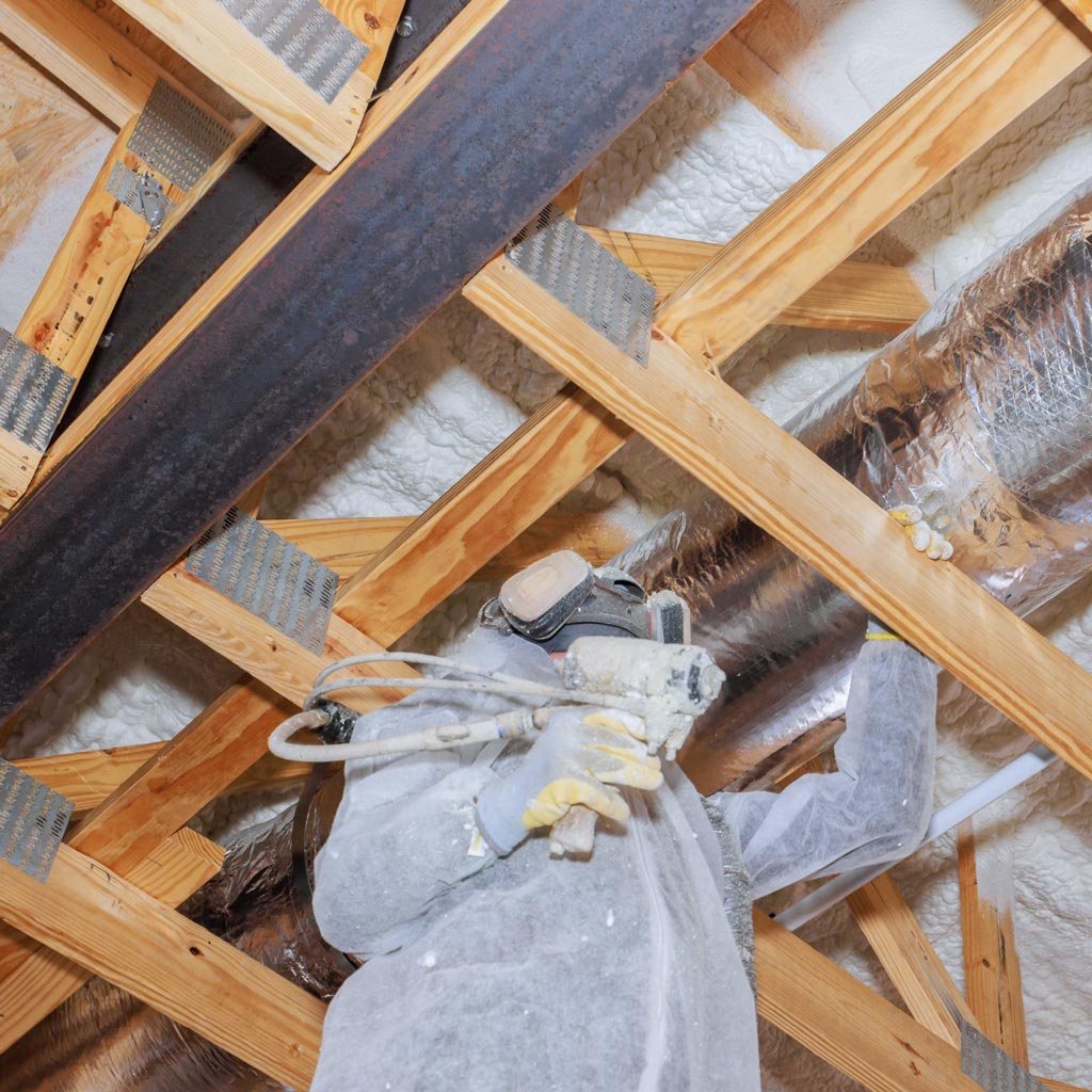 Man spraying foam insulation in attic
