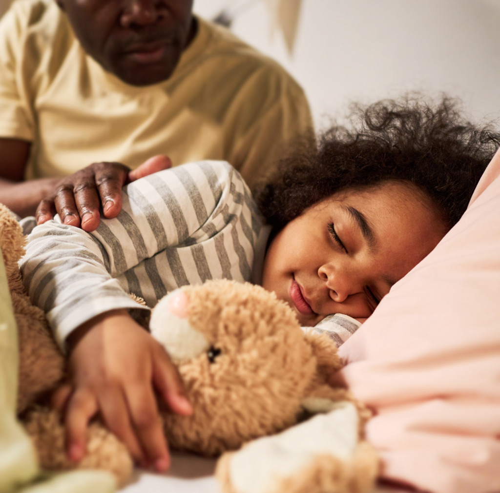 Dad comforts little girl sleeping with teddy bear